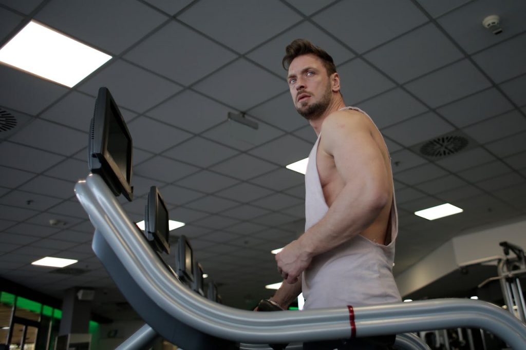 An athletic man using a treadmill in a modern gym, focusing on his workout.